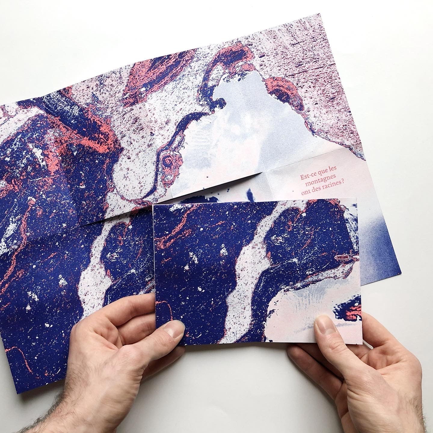 2 mains manipule une oeuvre picturale pouvant évoquer une pierre photographiée de très près