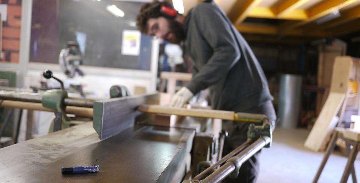 En action lors d'une initiation menuiserie travail du bois / dégauchisseuse