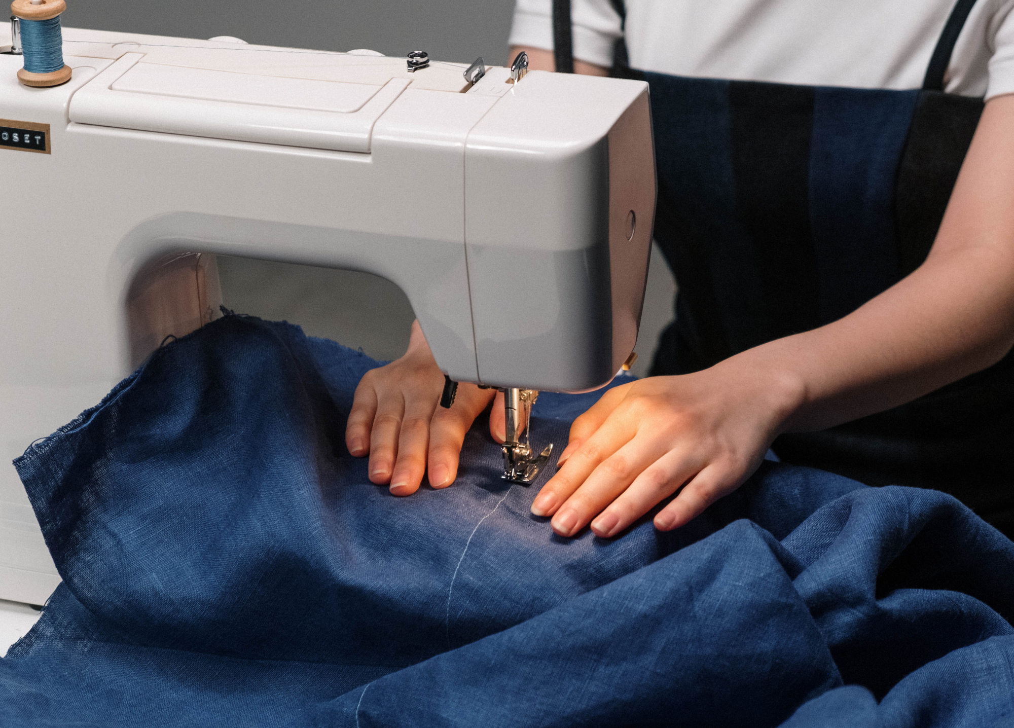 mains qui réparent un vêtement à la machine